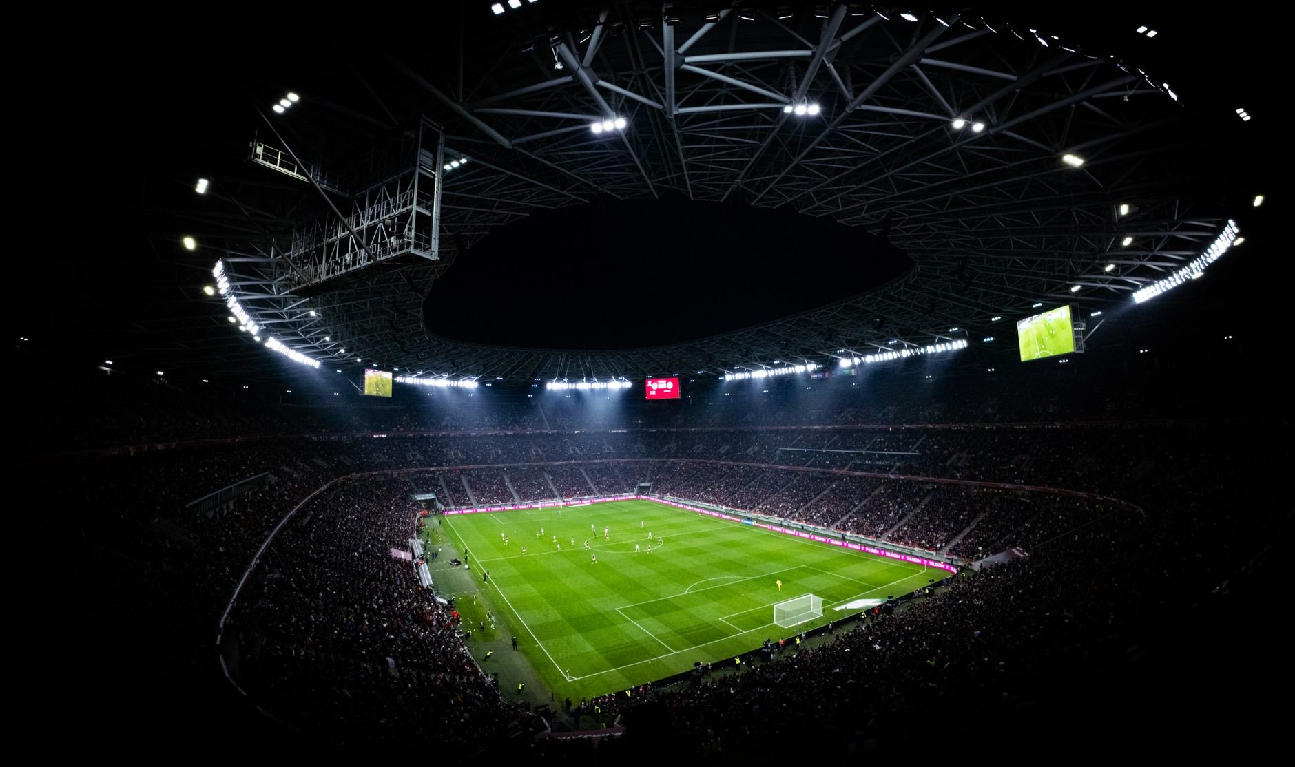 Aerial view of a night football match in a floodlit stadium